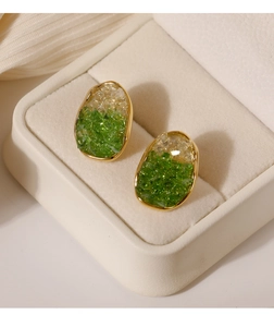 Primer plano de pendientes de cristal irregular con bordes dorados y textura de gema verde