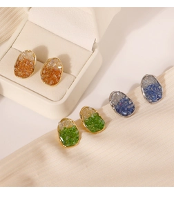 Detalle de tres pares de aretes de cristal irregular en ámbar, verde esmeralda y azul zafiro