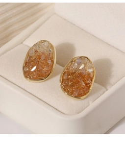 Detalle de pendientes dorados con incrustación de cristal ámbar degradado