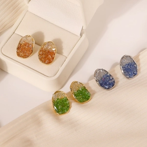 Tres pares de pendientes de cristal geométricos en azul verde y naranja sobre una bandeja