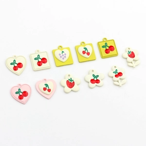 Macro shot of colorful alloy pendants with cherry and strawberry patterns for DIY jewelry