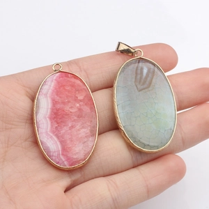 Handheld vintage oval agate pendants with pink and cyan textures in gold plating