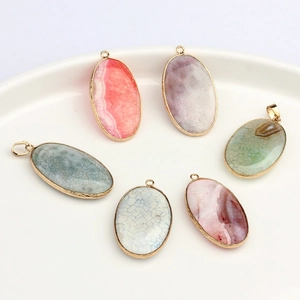 Oval natural agate pendants with gold metal edges in various colors on a ceramic tray