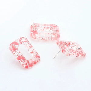 Detailed macro view of rectangular resin chain earrings with pink ink splash texture