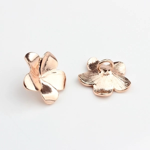 Macro detail of rose gold frangipani flower metal button showing front and back views