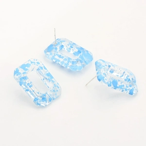 Detail of rectangular resin earrings with blue splatter pattern and silver metal studs