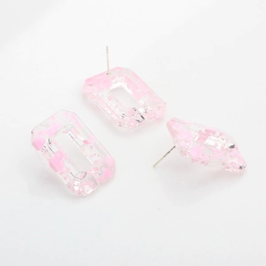 Detail view of rectangular resin stud earrings with pink ink splatter and metal pins
