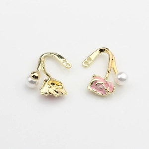 Detail of rose-shaped earrings with pink enamel, white faux pearls and gold hooks