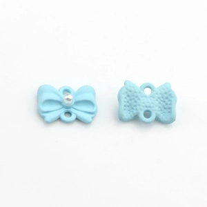 Dettaglio di ciondolo a fiocco azzurro con perla bianca e texture posteriore zigrinata