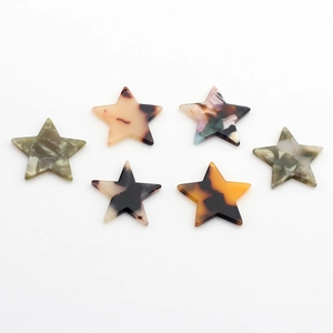 Close-up of star-shaped acetate resin pendants with amber tortoise and marble patterns
