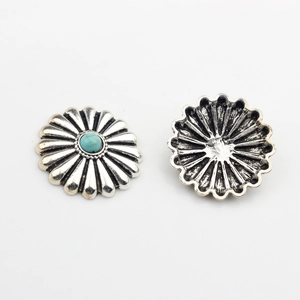 Macro detail of vintage daisy metal charm showing front turquoise inlay and back texture
