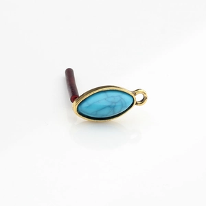 Detail of vintage golden alloy turquoise resin charm with oval horse-eye shape