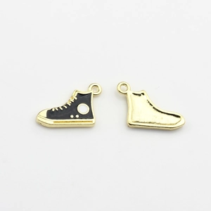 Macro detail of mini sneaker charm showing black enamel front and textured gold back