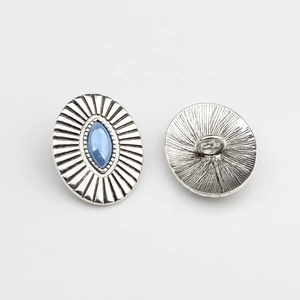 Close-up of vintage oval silver alloy button with sunburst texture and blue stone
