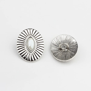 Detail of vintage silver oval alloy button with sunburst pattern and white resin inlay