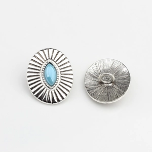 Macro detail of vintage silver oval button with blue marquise stone and sunburst texture