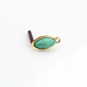 Detailed macro view of olive-shaped green resin earring pendant with gold alloy frame