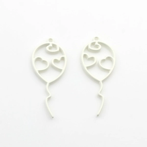 Macro view of matte white hollow balloon pendants with heart cutouts for jewelry making