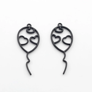 Detailed macro view of two black balloon charms with hollow heart patterns for DIY crafts