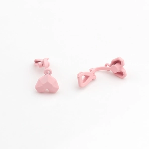 Close-up of pink faceted heart ear clips with matte finish for non-pierced ears