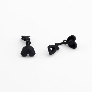 Detail view of matte black heart-shaped geometric stud earrings with faceted surface