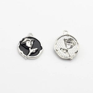 Detail of round silver-plated rose charms with black enamel finish for jewelry making