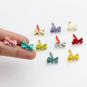 DIY colorful matte alloy bow charms for jewelry making shown next to finger for scale