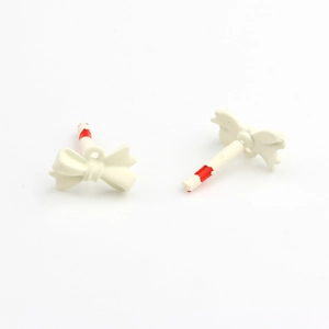 Macro detail of cream white mini bow charms for DIY earring and jewelry making