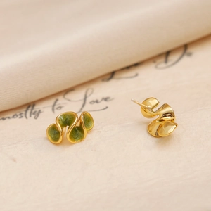 Boucles d'oreilles dorées asymétriques émaillées vert sur tissu en soie élégant