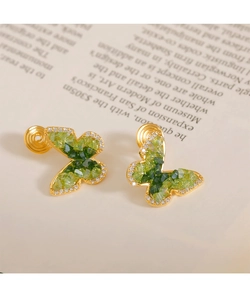 Détail de boucles d'oreilles clips papillon avec pierres vertes et dorure