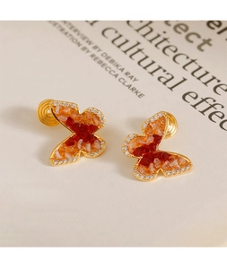 Détail de boucles d'oreilles clips papillon en cristal dégradé avec spirale dorée