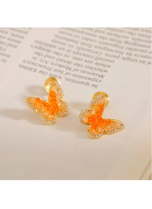 Détail macro de boucles d'oreilles papillon en cristal doré sur une page de livre
