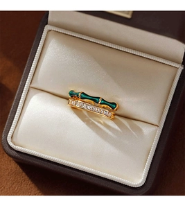 Gros plan d'une bague dorée double couche avec émail vert bambou et zircon dans son écrin
