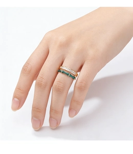 Détail de bague dorée en émail vert style bambou empilée avec anneau en zircon