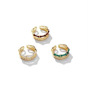 Bague double couche dorée avec détails en émail et zircons sur fond blanc épuré