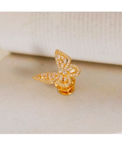 Nahaufnahme einer goldenen Schmetterlingsbrosche mit funkelndem Zirkonia auf Marmor
