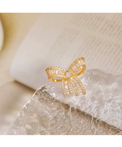Macro shot of gold bow ring with baguette-cut zircons on a crystal ice prop
