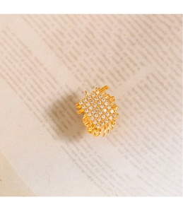 Close-up of golden woven geometric brooch with sparkling pave-set cubic zirconia stones