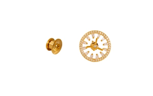 Macro detail of a gold clock-shaped brooch with white zirconia inlay and butterfly clasp