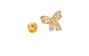 Detail of a golden bow brooch featuring sparkling zircon inlay and secure butterfly clasp