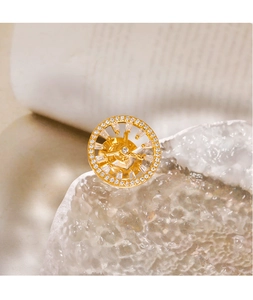 Macro detail of a gold geometric circular brooch with pavé micro-inlaid zircons