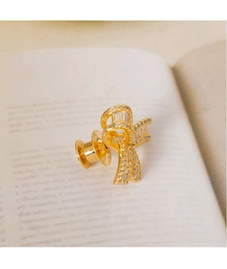 Macro shot of gold bow brooch with cubic zirconia inlay on a vintage book page