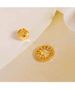 Macro detail of golden geometric clock brooch with hollow engraving and needle buckle