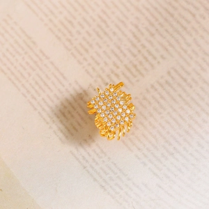 Luxurious geometric woven brooch with sparkling zircons on vintage paper background