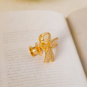 Elegant gold bow brooch with pavé zircon detail on a book for accessory styling