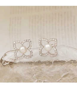 Detalle de pendientes de trébol con perla blanca natural y piedras de circonita