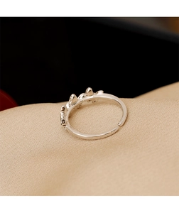 Gros plan d'une bague ajustable argentée avec zircons sur un tissu en satin doré
