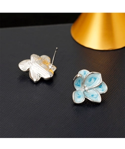 Macro shot of blue enamel flower earrings showing floral texture and silver metal backing