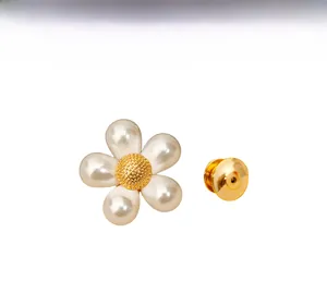 Détail macro de la broche marguerite avec perles blanches et cœur doré texturé