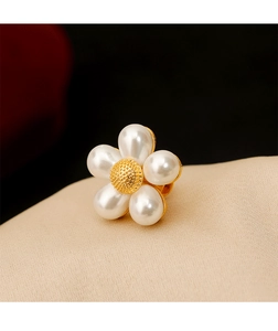 Détail macro d'une broche marguerite en perles blanches avec centre doré sur du tissu